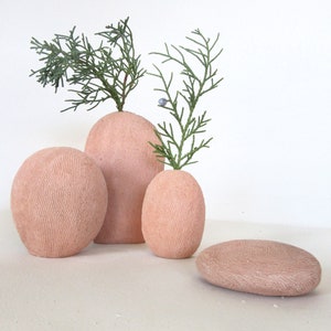May include: Three terracotta vases with a textured surface, two of which are holding sprigs of green foliage.