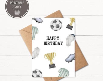 May include: A white birthday card with soccer-themed illustrations, including soccer balls, cleats, trophies, and jerseys. The words "HAPPY BIRTHDAY" are printed in bold black letters. The card is accompanied by a brown envelope.