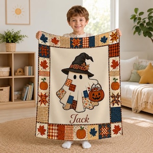 May include: A rectangular throw blanket featuring a central illustration of a ghost wearing a witch hat and holding a jack-o'-lantern bucket. The name Jack is printed below the ghost. The border has a patchwork pattern of leaves and plaid.