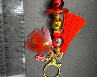 Suéter cárdigan rojo con dije de tijeras y borlas de hojas otoñales
