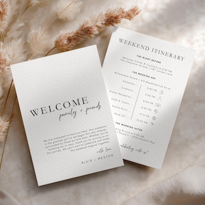 May include: Two white wedding itinerary cards with black text. One card reads "WELCOME family + friends" and includes a personal message. The other card lists the weekend's events, including times and locations.