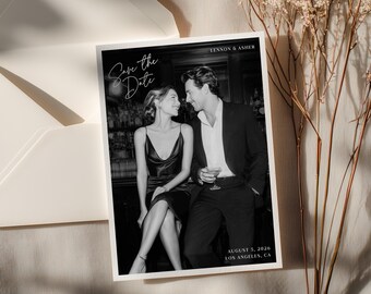 May include: Black and white save-the-date card featuring a couple in formal attire. The card reads "Save the Date" in cursive script, with the names "Lennon & Asher," and the date "August 5, 2026, Los Angeles, CA."