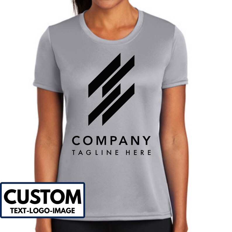 May include: A light gray t-shirt with a black logo and the words "COMPANY TAGLINE HERE" printed on the front. The shirt also has a white and black rectangle that says "CUSTOM TEXT-LOGO-IMAGE".