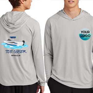 May include: Light gray hooded long-sleeve shirt with a boat graphic on the back that says "Tide Chaser" and "Bayville, NY". The front of the shirt has a circular logo that says "YOUR LOGO".