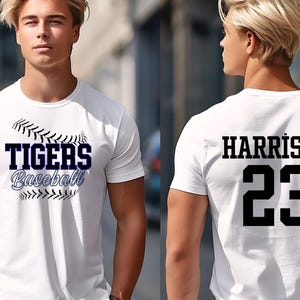 May include: White baseball t-shirt with "TIGERS Baseball" in navy blue and black stitching design on the front. The back of the shirt displays "HARRISON" and the number "23" in black.