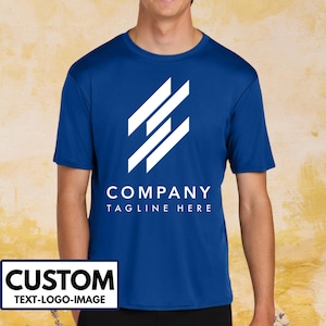 May include: Royal blue short-sleeve t-shirt with a white geometric logo and the text "COMPANY TAGLINE HERE". The shirt also has a white rectangle with the word "CUSTOM" and the text "TEXT-LOGO-IMAGE".