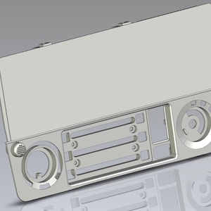 Op de afbeelding: Een lichtgrijs, 3D-geëngineerd elektronisch apparaat met een rechthoekig scherm en diverse cirkelvormige en rechthoekige componenten. Het apparaat heeft horizontale lijnen en cirkelvormige wijzerplaten.