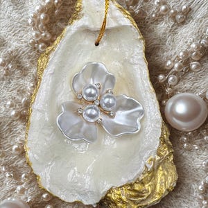 Gorgeous pearlescent oyster ornament with lovely flower embellishment. Hand applied gold painted edges: gifts, favors