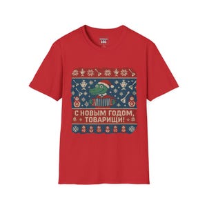 May include: Red t-shirt with a festive graphic. The graphic features a green alligator wearing a Santa hat and playing an accordion, surrounded by musical instruments and snowflakes. Text in Russian reads "Happy New Year, Comrades!"