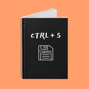 Puede incluir: Un cuaderno negro con espiral con el texto "CTRL + S" y un icono de disquete con la palabra "Guardar" en blanco. El cuaderno tiene páginas rayadas blancas, sobre un fondo naranja.