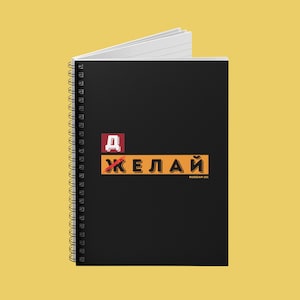 May include: Black spiral-bound notebook with white lined pages. The cover features the Russian word "Желай" in orange and yellow, with a red letter "Д" above it. The text "Russian 101" is in the bottom right corner.