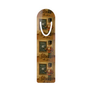 May include: A decorative bookmark with a repeating pattern of a nutcracker soldier in a red and gold uniform, standing in front of a chalkboard. The bookmark has a white loop at the top.