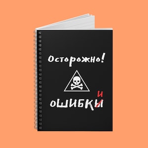以下が含まれることがあります： 白線入りのページがある黒いスパイラル綴じノート。表紙には白い文字と、三角形の中の白いドクロと骨のシンボルが描かれています。「Осторожно！」という言葉がシンボルの上にあり、「ошибки」が下にあり、「и」という言葉は赤色です。