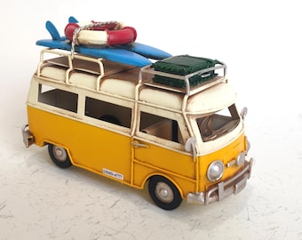 May include: A yellow and white miniature van with a surfboard, life preserver, and luggage on top. The van has black tires and a license plate that reads "23040-4777".