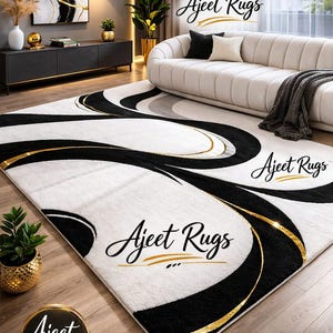May include: A white rug with black and gold abstract designs. The rug features curved lines and swirls, with gold accents. The rug is placed on a wooden floor, and the text "Ajeet Rugs" is visible.