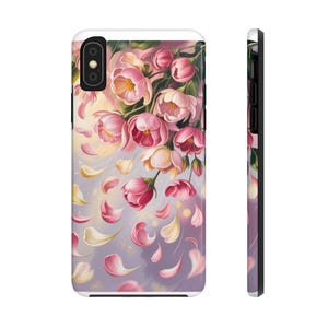 Peut inclure: Coque de téléphone blanche ornée d'un motif floral de fleurs roses et crème avec des pétales qui tombent. Le boîtier a une finition brillante et un bord noir, avec une découpe pour l'appareil photo en haut à gauche.