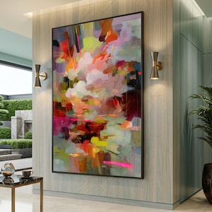 May include: A large rectangular wall art piece featuring an abstract composition of layered brushstrokes in vibrant shades of magenta, bright orange, lime green, deep red, and soft white, displayed in a thin black frame on a paneled wall.