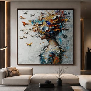 May include: A square oil painting in a dark frame depicting the profile of a person whose head dissolves into a swarm of colourful butterflies. The artwork features thick, textured brushstrokes in shades of orange, blue, yellow, and white.