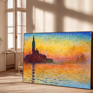 以下が含まれることがあります： 水面上のカラフルな夕日を描いた、大きな額入りのアートワーク。建物のシルエットが特徴です。絵画は、青、黄、オレンジ、赤の鮮やかな色合いを使用しています。アートワークは、植物と窓のある明るい部屋に展示されています。
