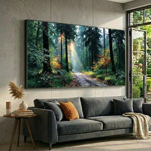 Könnte beinhalten: Ein großes rechteckiges Wandbild, das einen dichten Wald mit hohen dunklen Bäumen, einem sonnendurchfluteten Pfad und leuchtend grünem und orangefarbenem Laub zeigt. Das Kunstwerk hängt an einer hellgrauen Wand über einem dunkelgrauen Sofa.