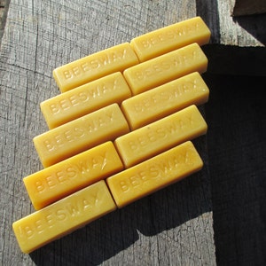 May include: A stack of eight yellow beeswax blocks, each with the word "Beeswax" printed on the front.