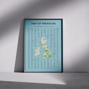May include: A framed poster titled "MAP OF PARKRUNS" showing a map of the UK and Ireland. The map is light blue with green and white dots. The poster is in a black frame and leans against a wall.