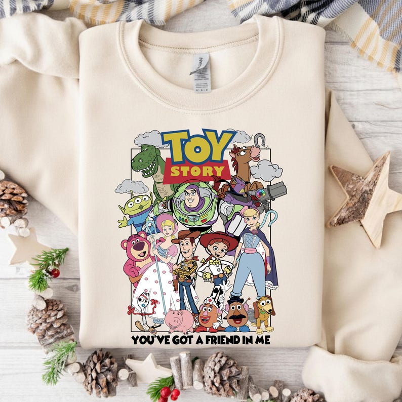 May include: Cream-coloured sweatshirt with a vibrant graphic of characters from the animated film "Toy Story." The design includes the words "Toy Story" and "You've Got a Friend in Me."