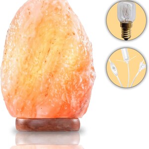 Peut inclure: Une lampe de sel de l'Himalaya avec une surface rugueuse, orange-rose, mont&eacute;e sur une base en bois fonc&eacute;. La lampe est allum&eacute;e, d&eacute;gageant une lueur chaleureuse. Comprend une ampoule et un cordon d'alimentation.