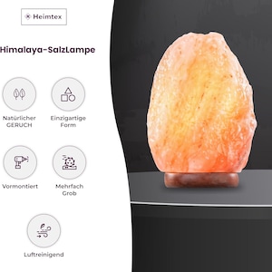 Peut inclure: Lampe de sel de l'Himalaya &agrave; la texture naturelle et rugueuse. La lampe d&eacute;gage une lueur orange chaude et repose sur une petite base en bois marron. L'image comprend le texte "Heimtex" et "Himalaya-Salzlampe".