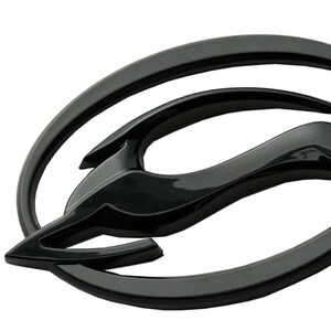 Può includere: Un emblema nero lucido raffigurante una gazzella stilizzata che salta all'interno di una cornice ovale. La gazzella è raffigurata in una posa dinamica, con le zampe distese. L'emblema ha un design elegante e moderno.