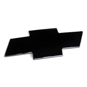 Peut inclure: Un emblème Chevrolet noir brillant avec une bordure argentée, en forme de nœud papillon. Ce symbole de la marque automobile est présenté sur un fond blanc.
