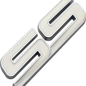 Könnte beinhalten: Ein silbernes und weißes Emblem mit den Buchstaben "SC" in einer stilisierten Schriftart. Die Buchstaben haben eine weiße Innenseite, einen silbernen Umriss und einen schwarzen Innenrand, was einen 3D-Effekt erzeugt. Das Emblem ist wahrscheinlich für die Automobilindustrie, Maße in cm.