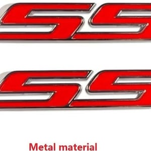 Peut inclure: Deux emblèmes SS rouges et chromés. Les emblèmes ont une bordure chromée brillante et un intérieur rouge vif. Le texte "Metal material" est au bas de l'image.