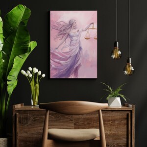 May include: A canvas print featuring a watercolor painting of a woman holding scales, set against a pink and purple background. The woman is depicted in a flowing white and purple gown, with long flowing hair. The artwork is framed and mounted on a wall.