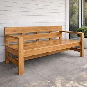 May include: A wooden outdoor bench with a natural finish. The bench has a slatted seat and backrest, with armrests on either side. The bench is made of solid wood and is designed for outdoor use. The bench is approximately 60 inches long.