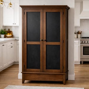 May include: A wooden cabinet with two doors and a dark chalkboard panel. The cabinet is a warm brown color and has a traditional design. The cabinet is in a kitchen setting.