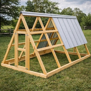 Può includere: Pollaio a forma di A in legno naturale con tetto in metallo ondulato. Il pollaio è costruito con travi di legno e ha una porta sul davanti. È posizionato su un prato erboso.