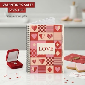 May include: A spiral-bound notebook with a red and pink heart pattern and the word "LOVE" on the cover. A red jewelry box with a silver necklace and a red envelope are also visible. Text reads "VALENTINE'S SALE! 25% OFF Shop unique gifts."