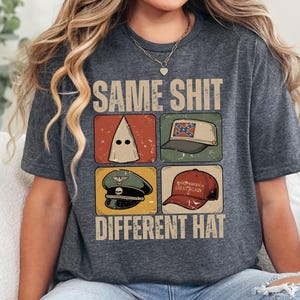 May include: Dark gray t-shirt with the text "SAME SHIT DIFFERENT HAT" above four images of hats. The hats include a white hood, a Confederate flag hat, a military hat, and a red "Make America Great Again" hat.