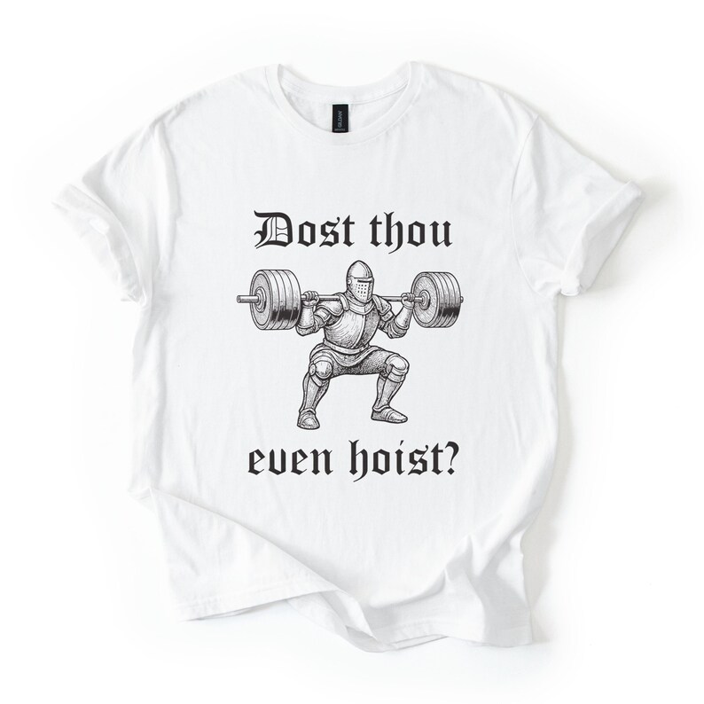 Op de afbeelding: Wit T-shirt met een zwarte afbeelding van een ridder die een halter heft. De tekst "Dost thou even hoist?" staat erboven en eronder. Het shirt heeft een ronde hals en korte mouwen.