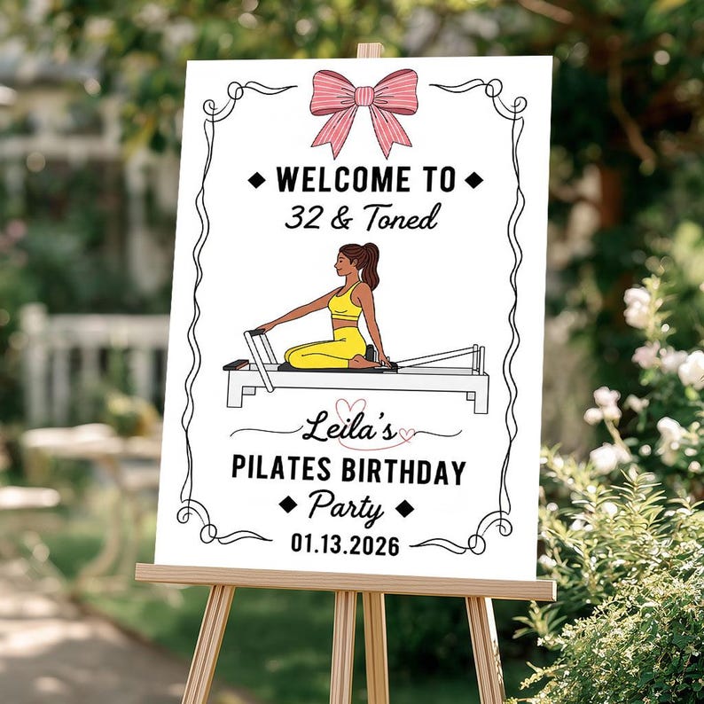 May include: A white sign on a wooden easel with the text "WELCOME TO 32 & TONED" and "Leila's PILATES BIRTHDAY Party 01.13.2026". The sign features a pink bow and a woman in yellow workout clothes on a Pilates reformer.