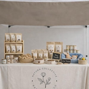 May include: A display table at a pet market, showcasing various pet food and treats. The table features bags of dog and cat food, treats, bowls, and a small bed. The table has a custom logo on the front.