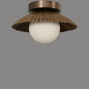 May include: A vintage-style ceiling light fixture. The fixture features a round, white globe light, encased in a scalloped, bronze-colored shade. The top of the fixture is a darker bronze color. The light is designed to be mounted on a ceiling.