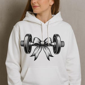 May include: White hoodie featuring a black barbell design tied with a bow. The barbell graphic is centrally placed on the front. The hoodie includes a front pocket and a drawstring hood, typical of this style of garment.