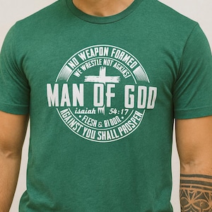 Pode incluir: Camiseta verde com gola redonda e um gráfico circular branco. O gráfico inclui o texto "NO WEAPON FORMED, WE WRESTLE NOT AGAINST, MAN OF GOD, Isaiah 54:17, AGAINST YOU SHALL PROSPER, FLESH & BLOOD."