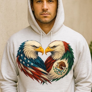May include: A light gray hoodie featuring a heart-shaped design of two eagles. One eagle has the American flag colors, and the other has the Mexican flag colors. The hoodie has a hood and a front pocket.
