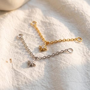 May include: Two jewelry chain connectors, one in gold tone and one in silver tone, each featuring a central star-shaped charm with a small embedded clear stone. Both chains have circular jump rings at each end for attachment to other jewelry pieces.