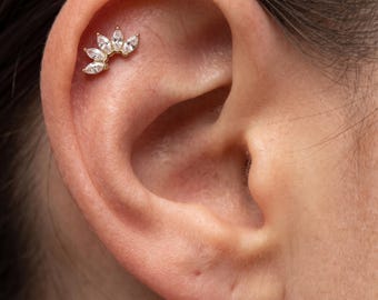 May include: A gold-toned ear cartilage piercing jewellery piece featuring a fan-shaped arrangement of five marquise-cut clear stones. The decorative element is positioned along the upper curve of the ear cartilage, showcasing a metallic base.