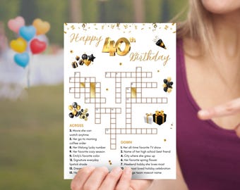 Puede incluir: Una tarjeta blanca con un mensaje dorado "Happy 40th Birthday" y un crucigrama. El crucigrama tiene pistas como "programa de televisión favorito" y "color favorito". Globos y confeti dorados y negros decoran la tarjeta.