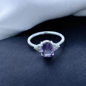 Może przedstawiać: Zestaw trzech ceramicznych kubków z nakrapianym, matowym wykończeniem. Kubki są w odcieniach kremu, jasnoszarym i ciemnoszarym. Każdy kubek ma prosty, nowoczesny design i zaokrąglony uchwyt.